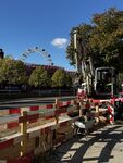 Ausbau des Wiener Fernkältenetzes Baustelle mit Bagger, Schubkarre und Absperrung vor Bäumen und einem Riesenrad im Hintergrund