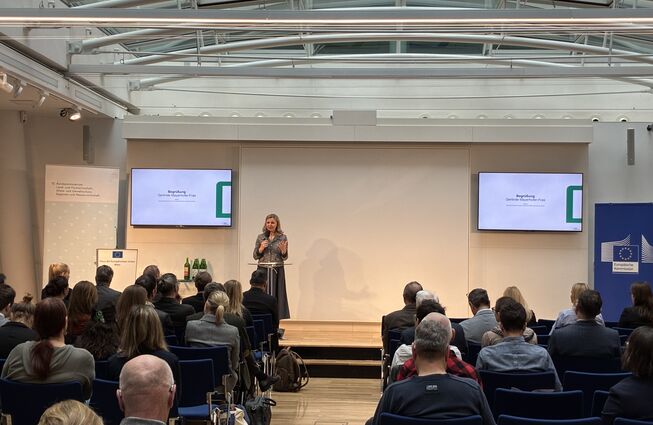 Grafik mit Darstellung KPC-Geschäftsführerin Gerline Mayerhofer-Fras bei Präsentation, mit Link zur Nachlesewebseite