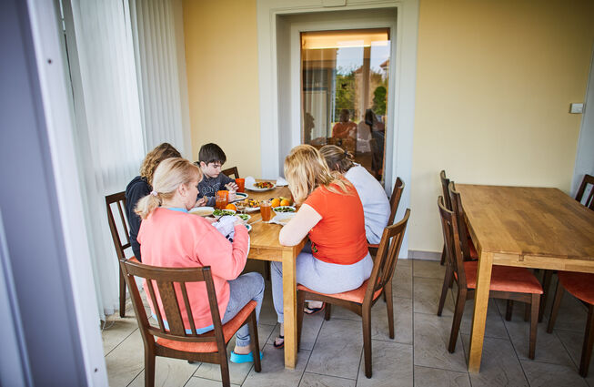 Sinnbildliche Darstellung eines in einem Ankunftszentrum am Tisch zusammensitzenden Personenkreises